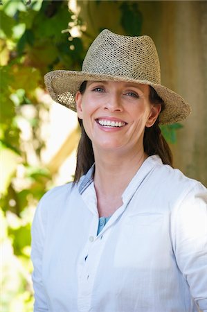 Portrait of a beautiful mature woman wearing hat and smiling Stock Photo - Premium Royalty-Free, Code: 6108-05870251