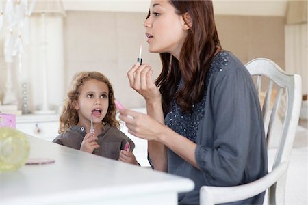 Young woman and little girl applying lip gloss at dressing table Foto de stock - Sin royalties Premium, Código: 6108-05870228
