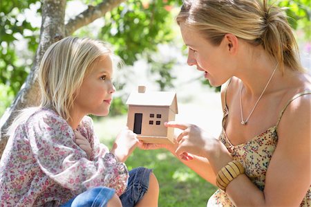 Little girl and her mother holding dollhouse outdoors Fotografie stock - Premium Royalty-Free, Codice: 6108-05870356