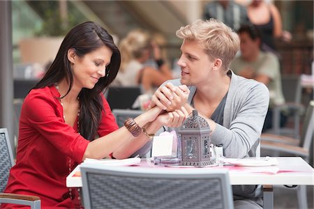 Young man holding hands of his girlfriend in a restaurant Stock Photo - Premium Royalty-Free, Code: 6108-05870305