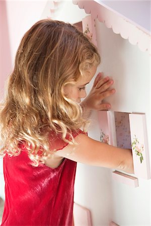 Cute little girl playing with a dollhouse Foto de stock - Royalty Free Premium, Número: 6108-05870461