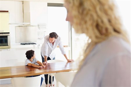 simsearch:6108-05871624,k - Close-up of a woman with focus on father and son talking to each other in the background Foto de stock - Royalty Free Premium, Número: 6108-05870409