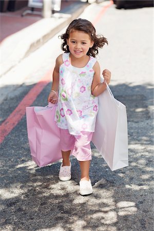 simsearch:6108-05870485,k - Cute little girl walking with shopping bags in hands Foto de stock - Royalty Free Premium, Número: 6108-05870439