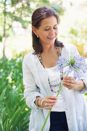 Smiling woman holding a single flower in hand Stock Photo - Premium Royalty-Free, Code: 6108-05870552