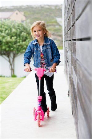 simsearch:6108-05870619,k - Portrait of a smiling girl riding a push scooter Fotografie stock - Premium Royalty-Free, Codice: 6108-05870567