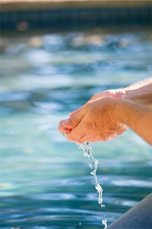 Close-up of a man's hand touching the water of the swimming pool Stock Photo - Premium Royalty-Free, Code: 6108-05870509