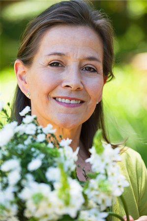 Portrait of a woman holding a bunch of flowers outdoors Stock Photo - Premium Royalty-Free, Code: 6108-05870539