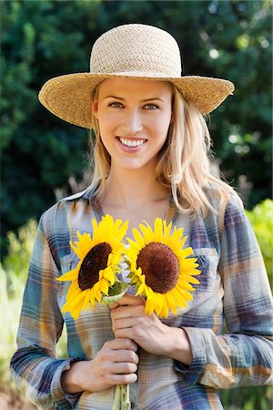 simsearch:6108-05872632,k - Portrait of a young woman holding sunflowers in a field Stock Photo - Premium Royalty-Free, Code: 6108-05870654