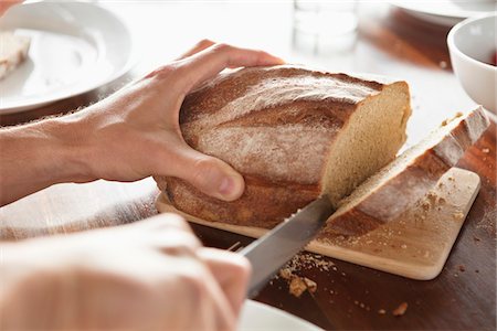 freshly baked bread - Close-up of a person's hand cutting bread Stock Photo - Premium Royalty-Free, Code: 6108-05870662