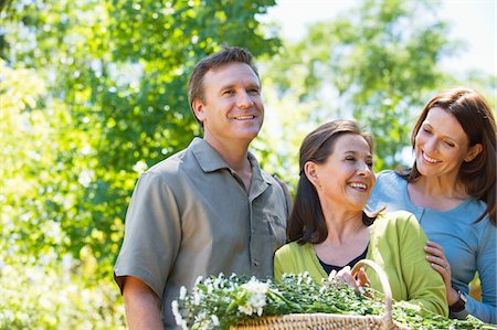 senior woman and son affection - Woman standing with his son and daughter in law while holding basket of flowers Stock Photo - Premium Royalty-Free, Code: 6108-05870690