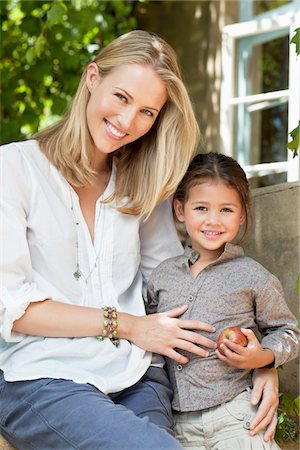 Daughter holding apple with mother smiling Stock Photo - Premium Royalty-Free, Code: 6108-05870631