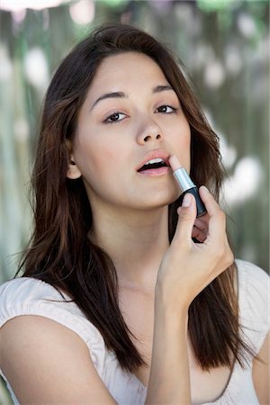 simsearch:6108-06905383,k - Portrait of a beautiful young woman applying lipstick Foto de stock - Sin royalties Premium, Código: 6108-05870798