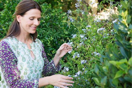 Smiling mature woman looking at flowers in garden Stock Photo - Premium Royalty-Free, Code: 6108-05870704