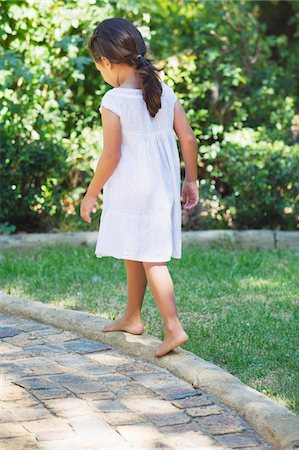 Rear view of a little girl walking in the garden Stock Photo - Premium Royalty-Free, Code: 6108-05870717
