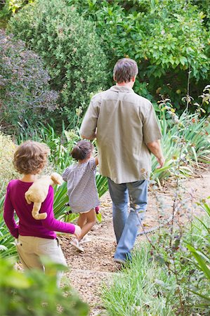 father and daughter of backside in garden - Father with two children walking in a garden Stock Photo - Premium Royalty-Free, Code: 6108-05870726