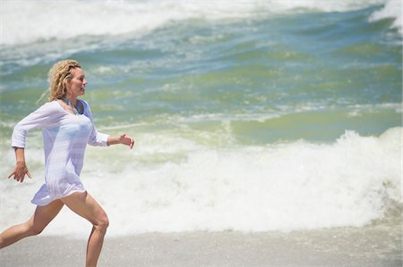 running to surf - Side profile of a beautiful woman running on the beach Foto de stock - Sin royalties Premium, Código: 6108-05870883