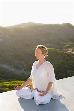 sitting on terrace - Mid adult woman meditating Stock Photo - Premium Royalty-Free, Code: 6108-05870888