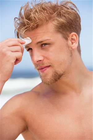 Young man applying moisturizer on his face Stock Photo - Premium Royalty-Free, Code: 6108-05871048