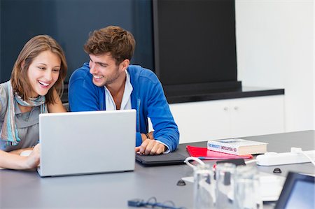 simsearch:6108-05870070,k - University students smiling while using laptop in classroom Foto de stock - Sin royalties Premium, Código: 6108-05871259