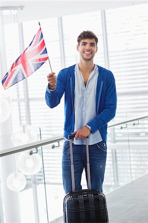 Portrait of a man holding British flag and a suitcase at an airport Stock Photo - Premium Royalty-Free, Code: 6108-05871289