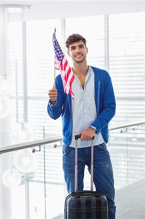 patriotique - Portrait d'un homme tenant un drapeau américain et une valise à l'aéroport Photographie de stock - Premium Libres de Droits, Code: 6108-05871300