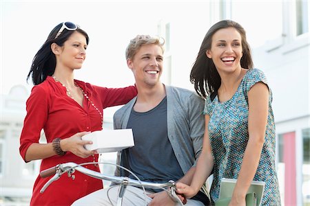 Smiling young man with two women cycling Stock Photo - Premium Royalty-Free, Code: 6108-05871444