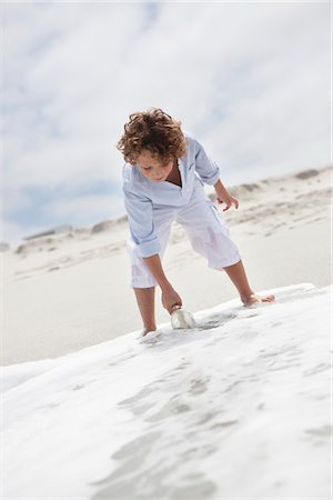 Boy putting bottle with message in water on beach Foto de stock - Sin royalties Premium, Código: 6108-05871573