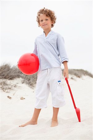 plastic toys - Boy holding toy shovel and ball on beach Stock Photo - Premium Royalty-Free, Code: 6108-05871577
