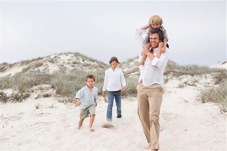 shoulder carry boy girl - Man walking on sand with their children Stock Photo - Premium Royalty-Free, Code: 6108-05871643
