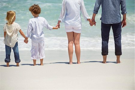 father son hold hands back - Couple with two children standing on the beach Stock Photo - Premium Royalty-Free, Code: 6108-05871620