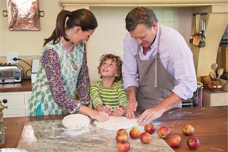 Cute little boy and his parents kneading dough at kitchen Stock Photo - Premium Royalty-Free, Code: 6108-05871797