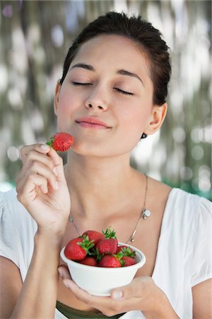 eating strawberry - Beautiful young woman holding a bowl of strawberries with her eyes closed Stock Photo - Premium Royalty-Free, Code: 6108-05871730