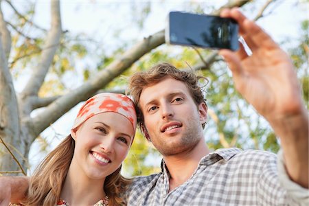 smile couple taking picture phone - Young couple taking a picture of themselves with a mobile phone Stock Photo - Premium Royalty-Free, Code: 6108-05871855