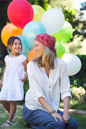 diverse happy children - Mother looking at a little girl holding balloons Stock Photo - Premium Royalty-Free, Code: 6108-05871940