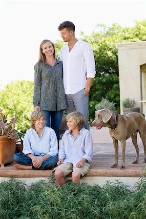 Famille avec leur chien à l'extérieur de la maison Photographie de stock - Premium Libres de Droits, Code: 6108-05872044