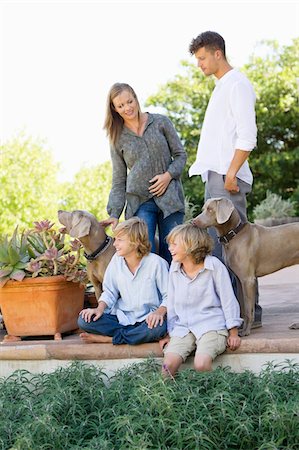 family stroke sit - Family having a good time outside house with two dogs Stock Photo - Premium Royalty-Free, Code: 6108-05872088