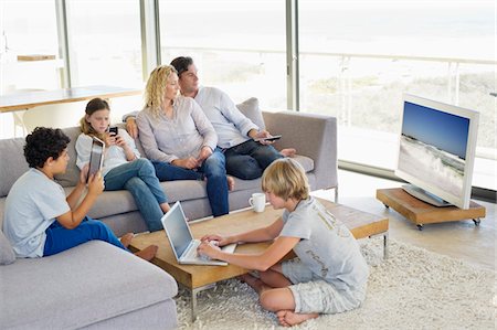 simsearch:6108-06166923,k - Couple watching television set while their children busy in different activities Stock Photo - Premium Royalty-Free, Code: 6108-05872035