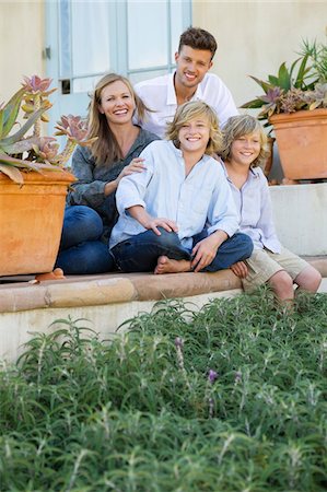 position assise en tailleur - Portrait d'une famille heureuse, assis devant leur maison Photographie de stock - Premium Libres de Droits, Code: 6108-05872038