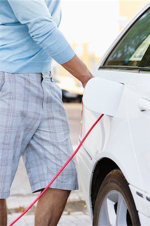 electric car charging - Mid section view of a mid adult man charging the electric car Stock Photo - Premium Royalty-Free, Code: 6108-05872254