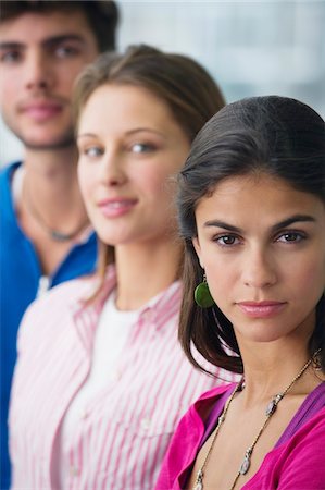 Portrait of three university students standing in a line with focus on a woman Stock Photo - Premium Royalty-Free, Code: 6108-05872267