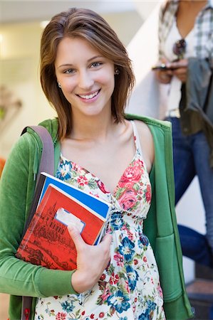 Portrait of a beautiful woman holding books in hand and smiling Stock Photo - Premium Royalty-Free, Code: 6108-05872270