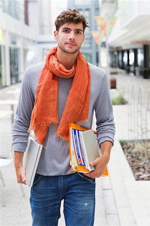 estudiante universitario - Portrait of a man walking with books and a laptop in hands Foto de stock - Sin royalties Premium, Código: 6108-05872274