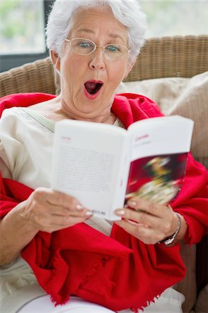 relaxed older lady reading book - Senior woman reading a magazine and looking surprised Foto de stock - Sin royalties Premium, Código: 6108-05872355
