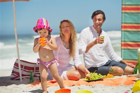 sky family - Girl drinking juice on the beach Stock Photo - Premium Royalty-Free, Code: 6108-05872555