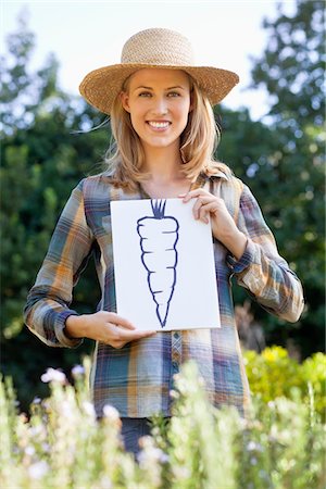 Portrait of a young woman showing carrot painting in a field Fotografie stock - Premium Royalty-Free, Codice: 6108-05872573