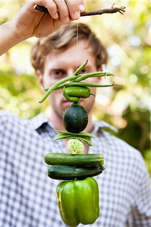 Homme tenant légumes suspendus sur une branche Photographie de stock - Premium Libres de Droits, Code: 6108-05872650