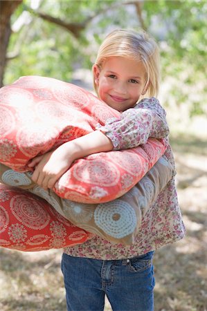 simsearch:6108-05870619,k - Portrait of a smiling little girl carrying pillows outdoors Fotografie stock - Premium Royalty-Free, Codice: 6108-05872654