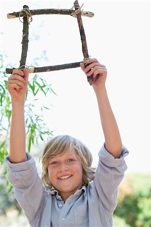 Portrait d'un mignon petit garçon tenant à cadre de bois flotté avec les bras élevés en plein air Photographie de stock - Premium Libres de Droits, Code: 6108-05872663