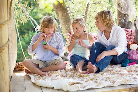 friends photo of boys and girls - Children blowing bubble wand in tree house Stock Photo - Premium Royalty-Free, Code: 6108-05872692