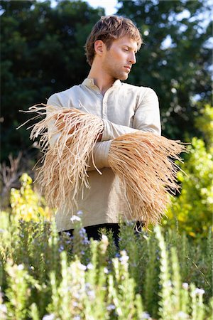 Young man standing in a field as scarecrow Stock Photo - Premium Royalty-Free, Code: 6108-05872600